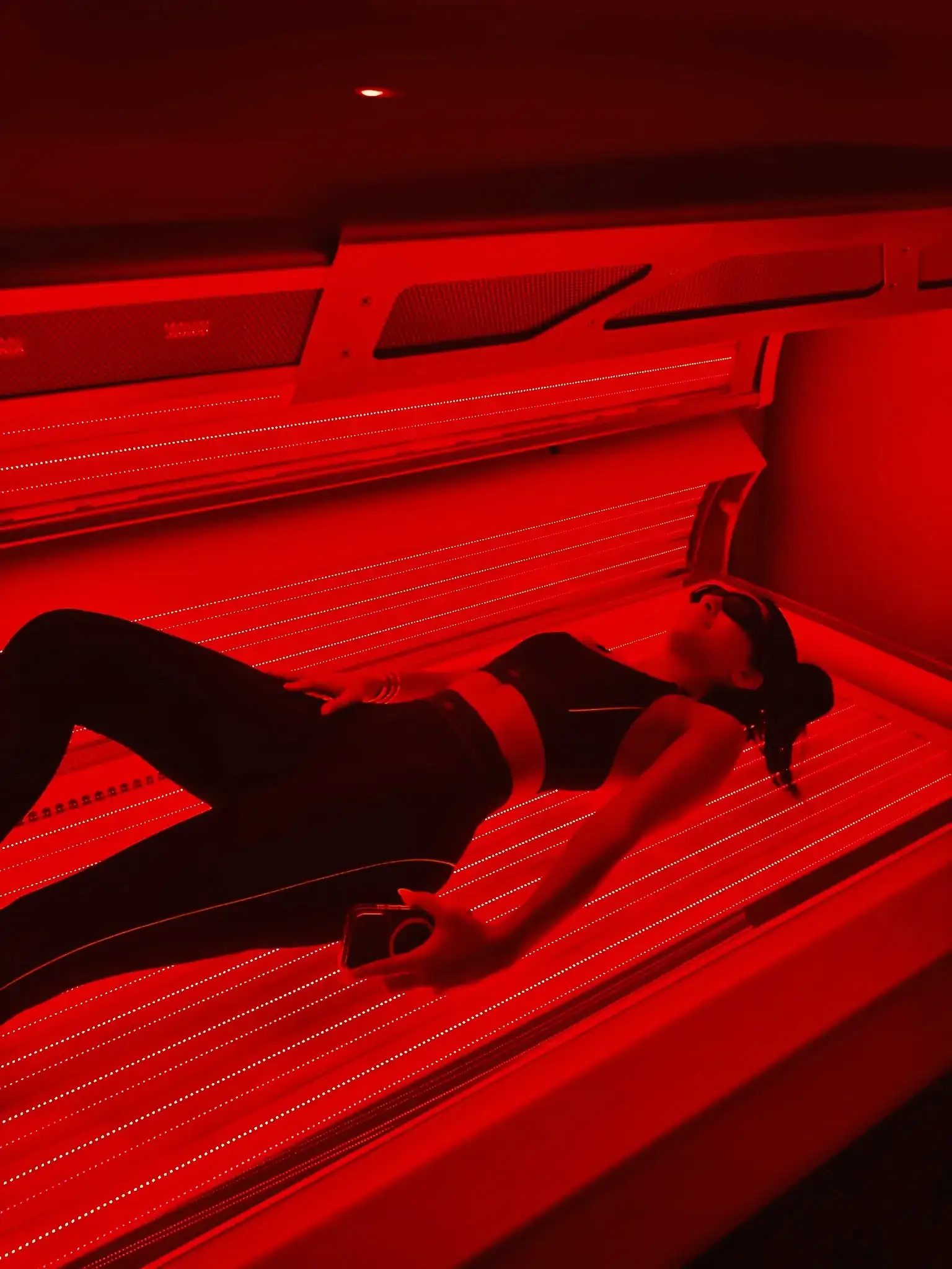 Client relaxing in the Merican M6N full-body red light therapy bed used for the Red Glow membership at Naturally Bronzed